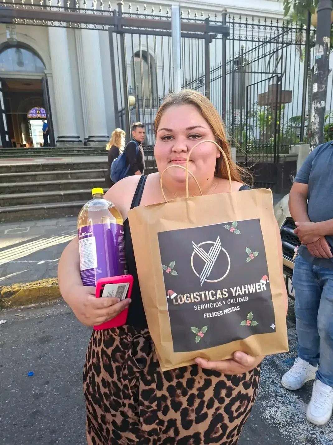 Joven recibe su bolsa de «Felices Fiestas» de Logísticas Yahweh en la acera