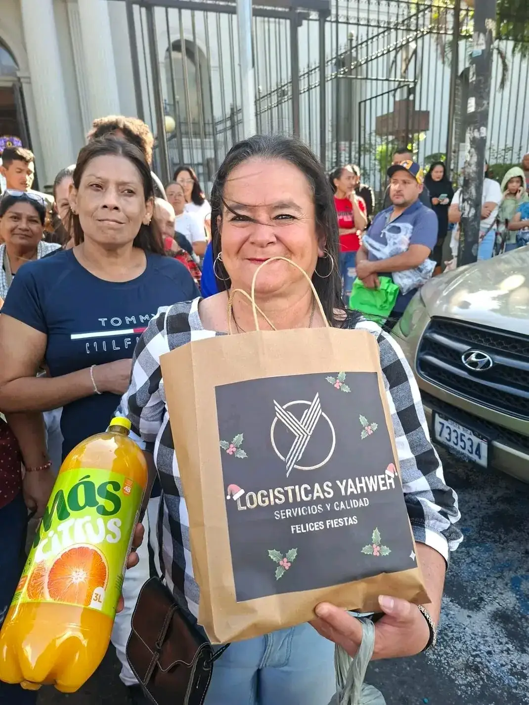 Dos mujeres, una de ellas con la bolsa de «Felices Fiestas» de Logísticas Yahweh y una botella de refresco de tres litros